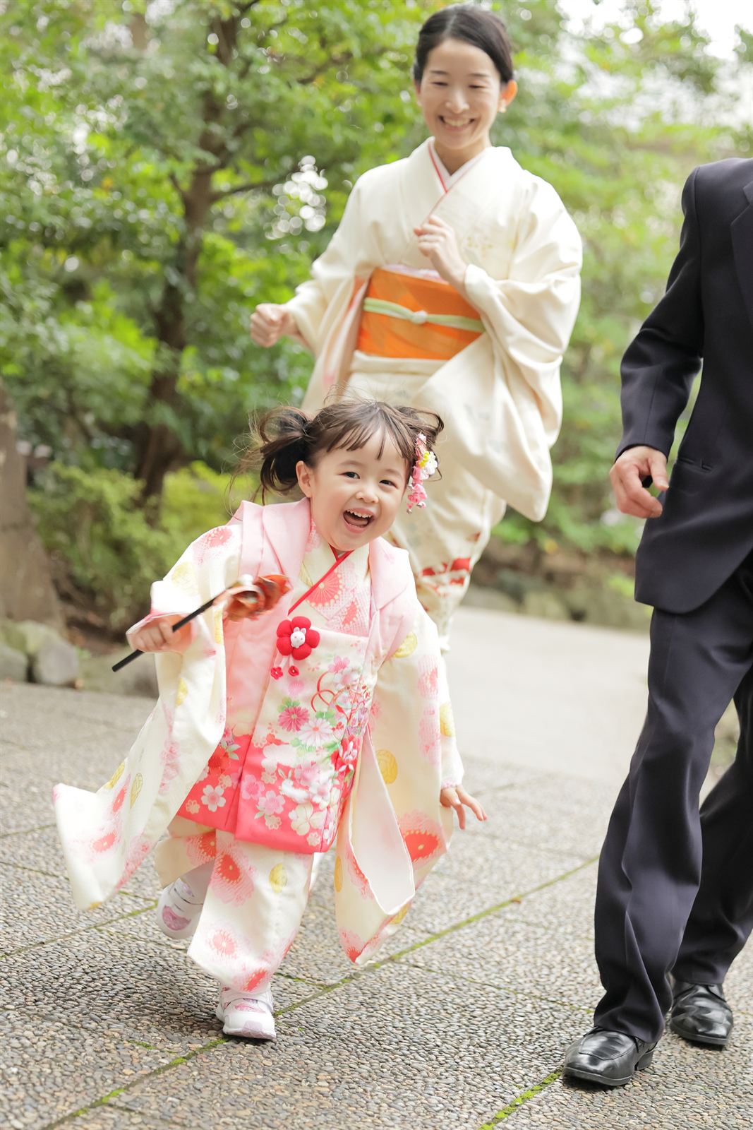 七五三で笑顔で駆ける女の子とご家族